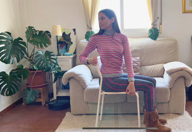 Mujer haciendo una torsion de yoga en una silla