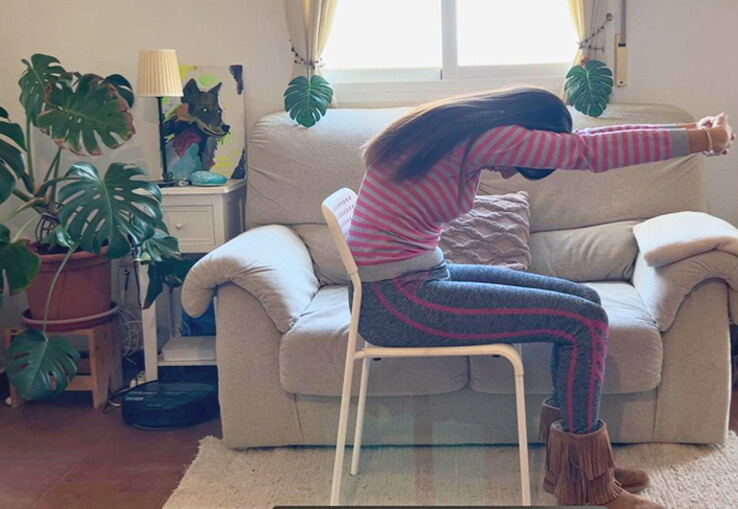 Mujer practicando yoga en una silla con brazos estirados