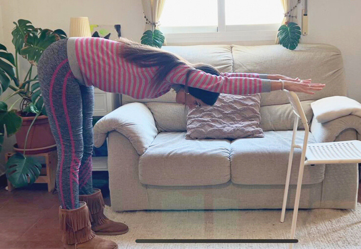 Mujer practicando yoga  estirando sus brazos en una silla